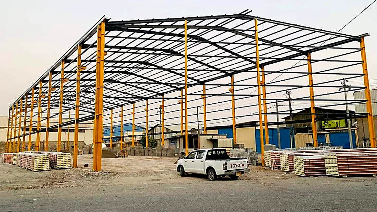 مبنى صناعي بهيكل فولاذي وأعمدة صفراء أثناء أعمال النصب